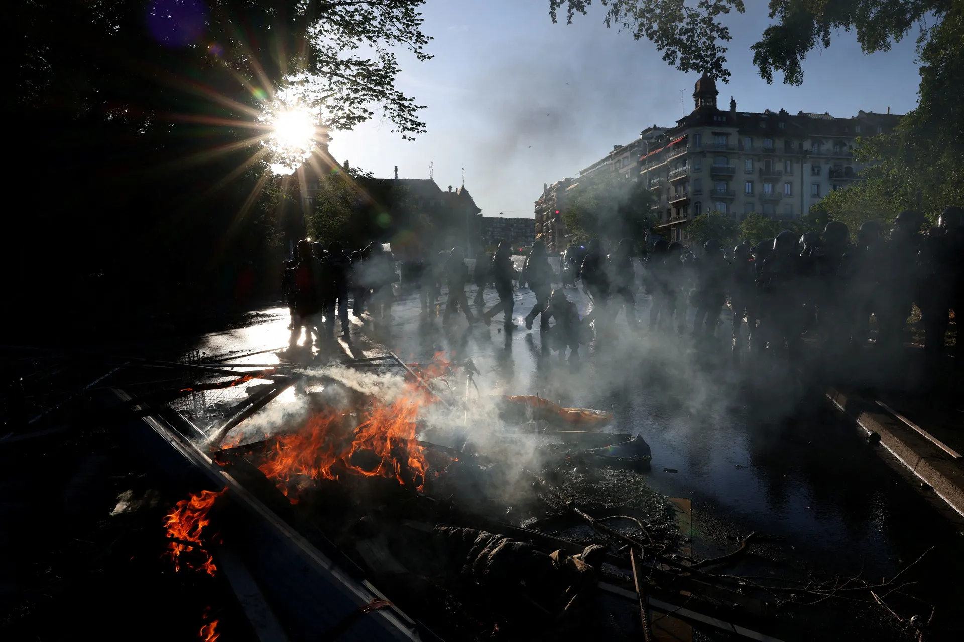 Riot police walk past fire as demonstrators hold banners during a protest against the upcoming G7 summit in Evian-les-Bains in France, in Geneva, Switzerland, June 14, 2026. REUTERS/Umit Bektas     TPX IMAGES OF THE DAY