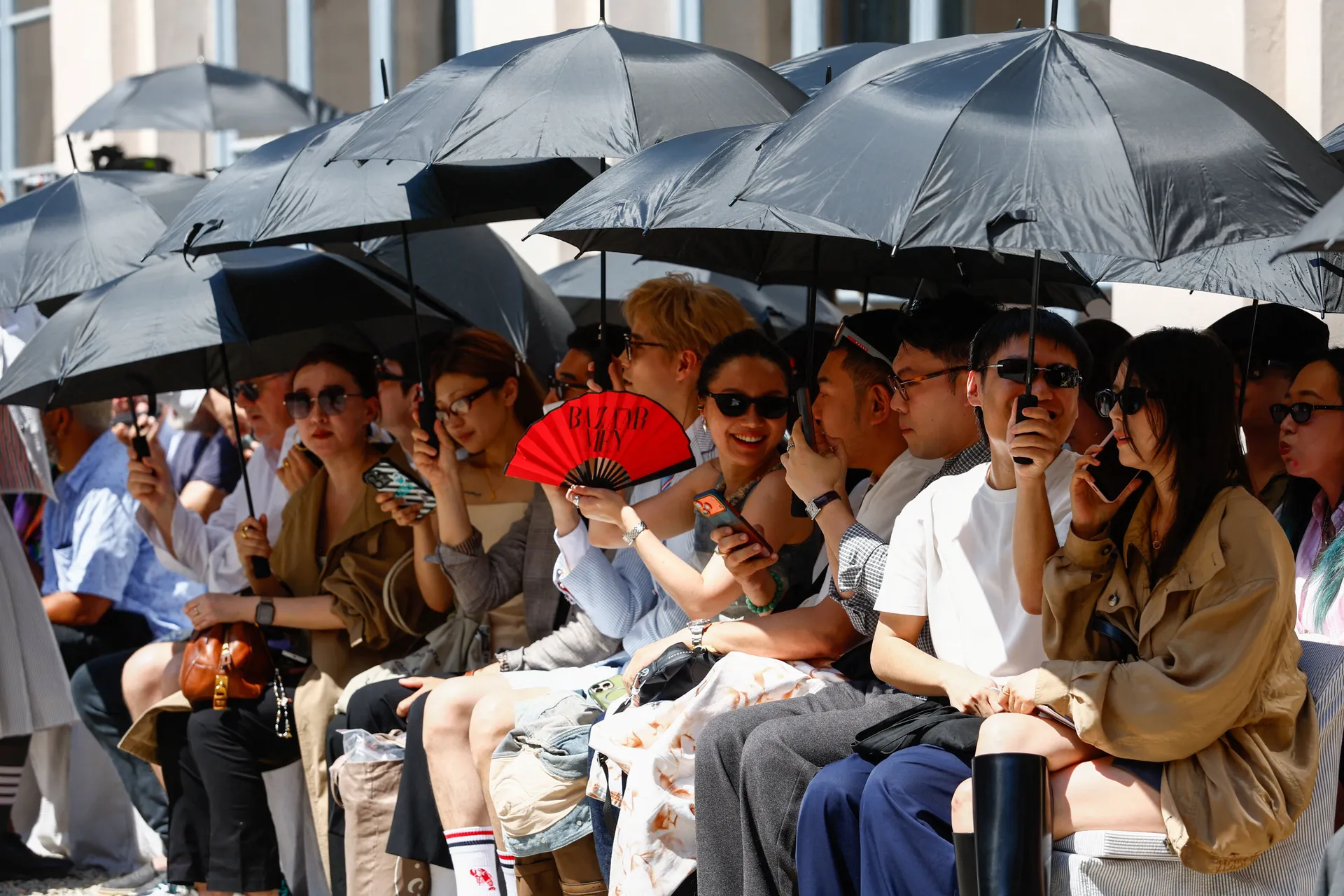 People shield themselves from the sun with umbrellas during Thom Browne’s Spring/Summer 2027 men’s collection show as part of Milan Fashion Week, in Milan, Italy, June 22, 2026. REUTERS/Alessandro Garofalo