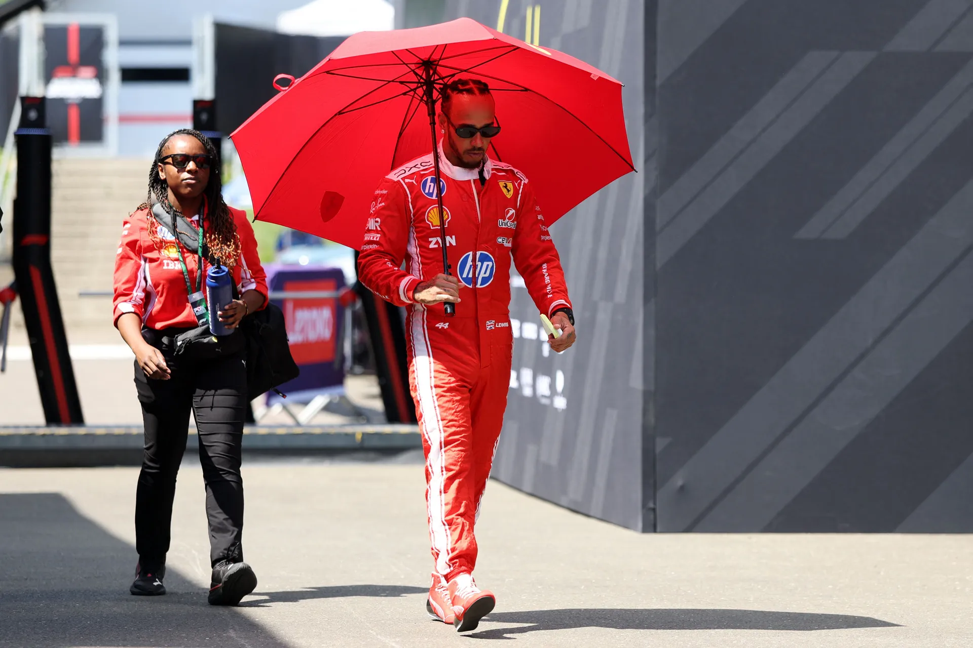 Formula Jedan F1 - Austrian Grand Prix - Red Bull Ring, Spielberg, Austria Ferrari's Lewis Hamilton nosi crveni kišobran kako bi se zaštitio od sunca 
