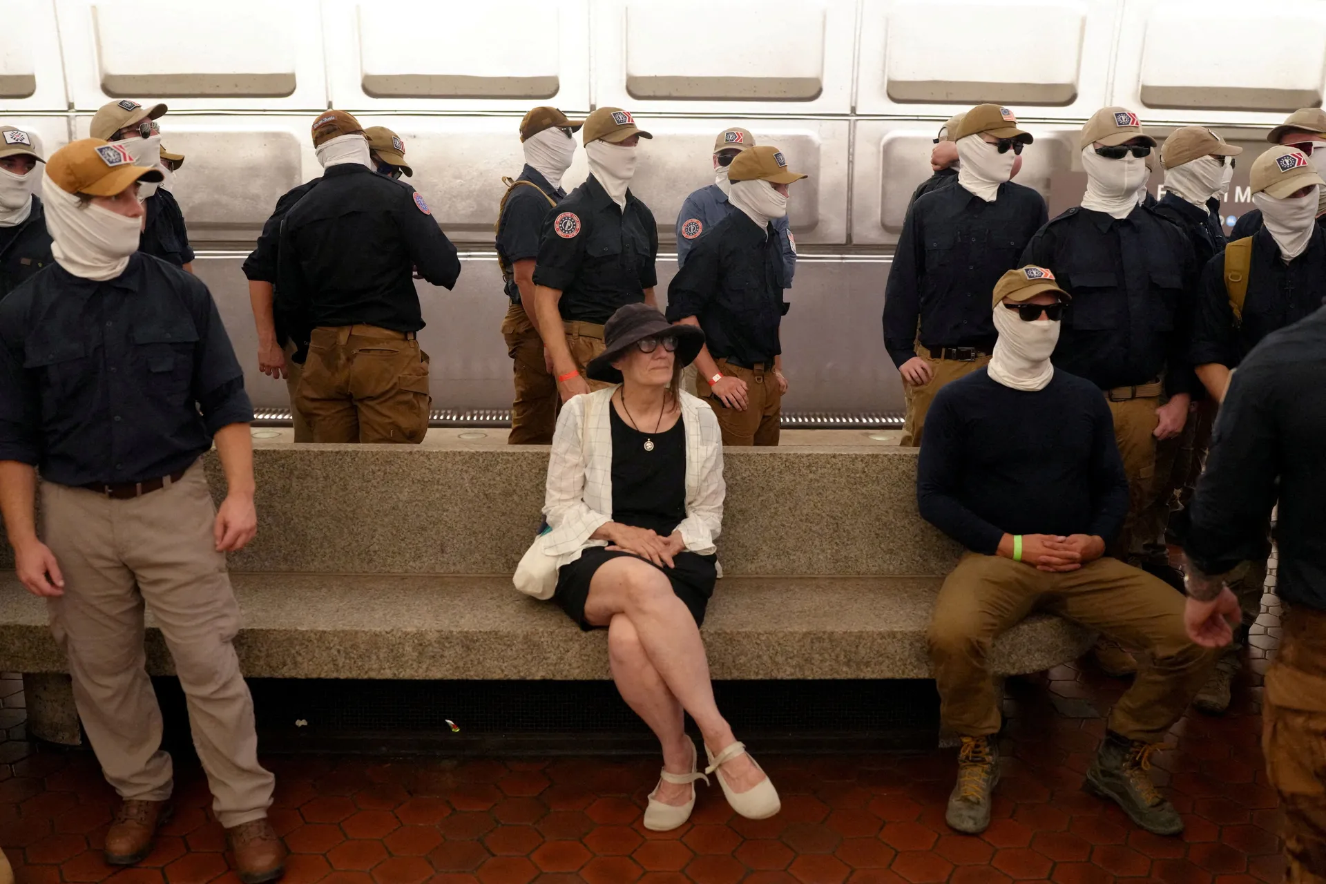 A commuter sits as members of the group Patriot Front stand at the Eastern Market metro station, on the 250th anniversary of U.S. independence in Washington, D.C., U.S., July 4, 2026. REUTERS/Nathan Howard     TPX IMAGES OF THE DAY