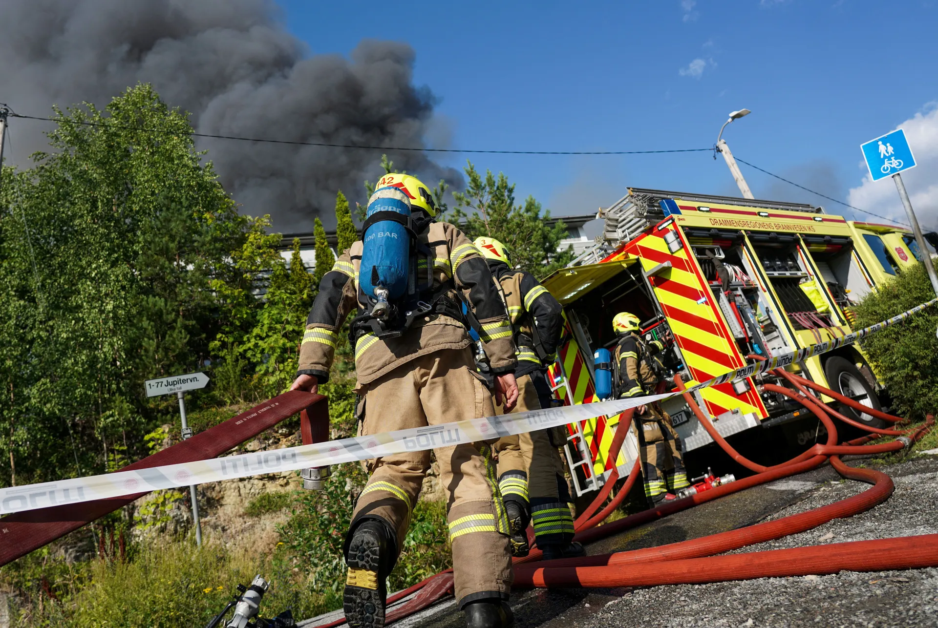 Firefighters work as smoke rises from a large fire that has spread from terraced houses in Krokstadelva, Drammen municipality, Norway, July 17, 2026. More than 50 homes were destroyed by fire on Friday near the city of Drammen in southern Norway as firefi