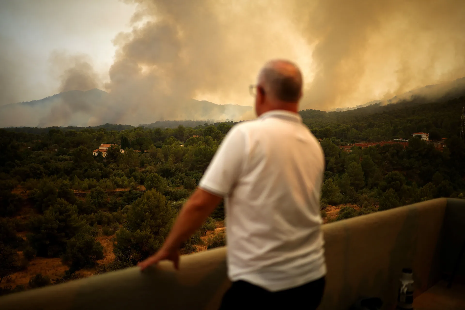 A man watches a wildfire on a mountain in Onda, Spain, July 27, 2026. REUTERS/Pedro Nunes
