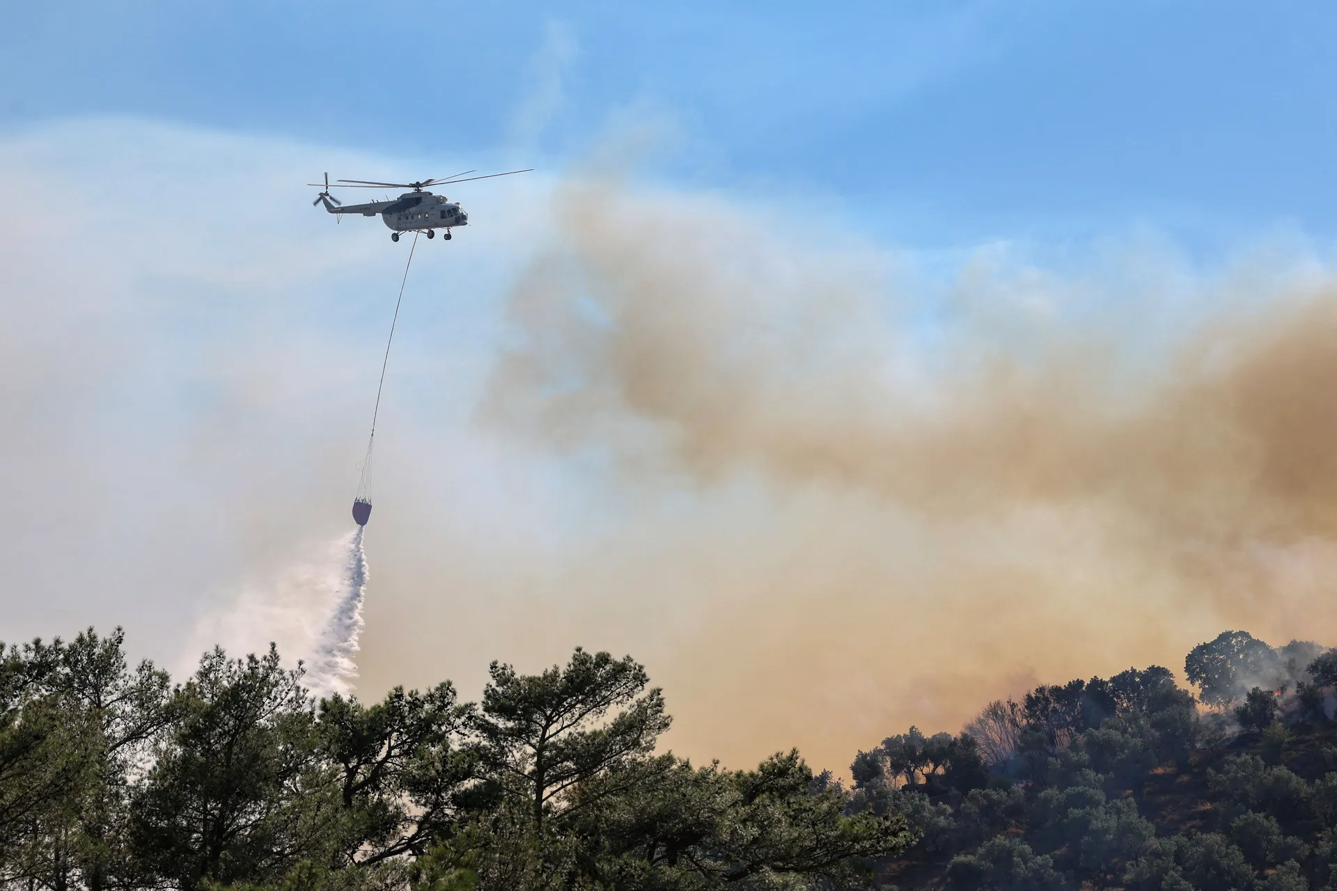 A firefighting helicopter makes a water drop as a wildfire burns next to the village of Plomari on the island of Lesbos, Greece, July 29, 2026. REUTERS/Elias Marcou