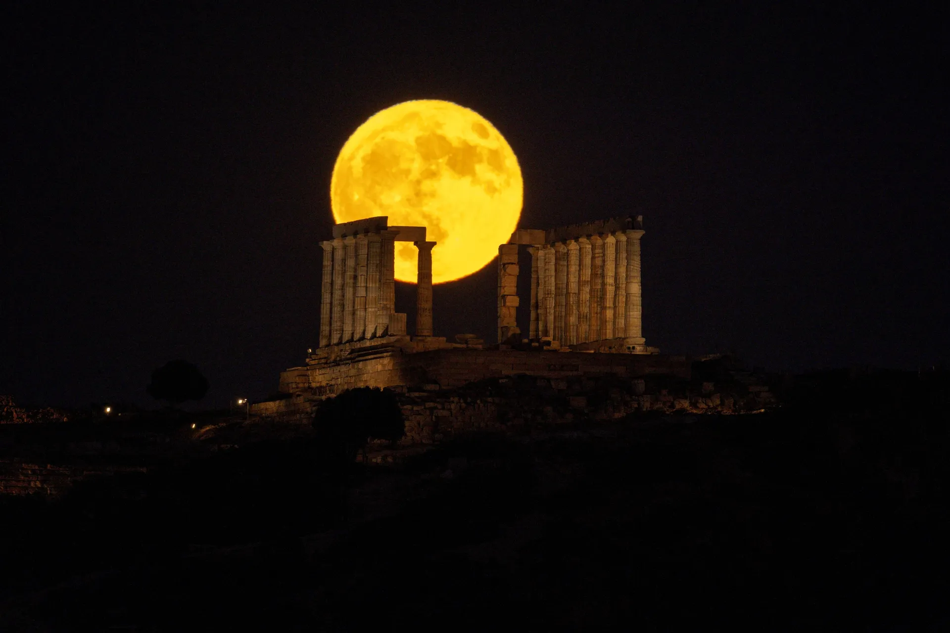 A full moon known as the "Buck Moon" rises behind the ancient Temple of Poseidon at Cape Sounion, south of in Athens, Greece, July 29, 2026. REUTERS/Louiza Vradi