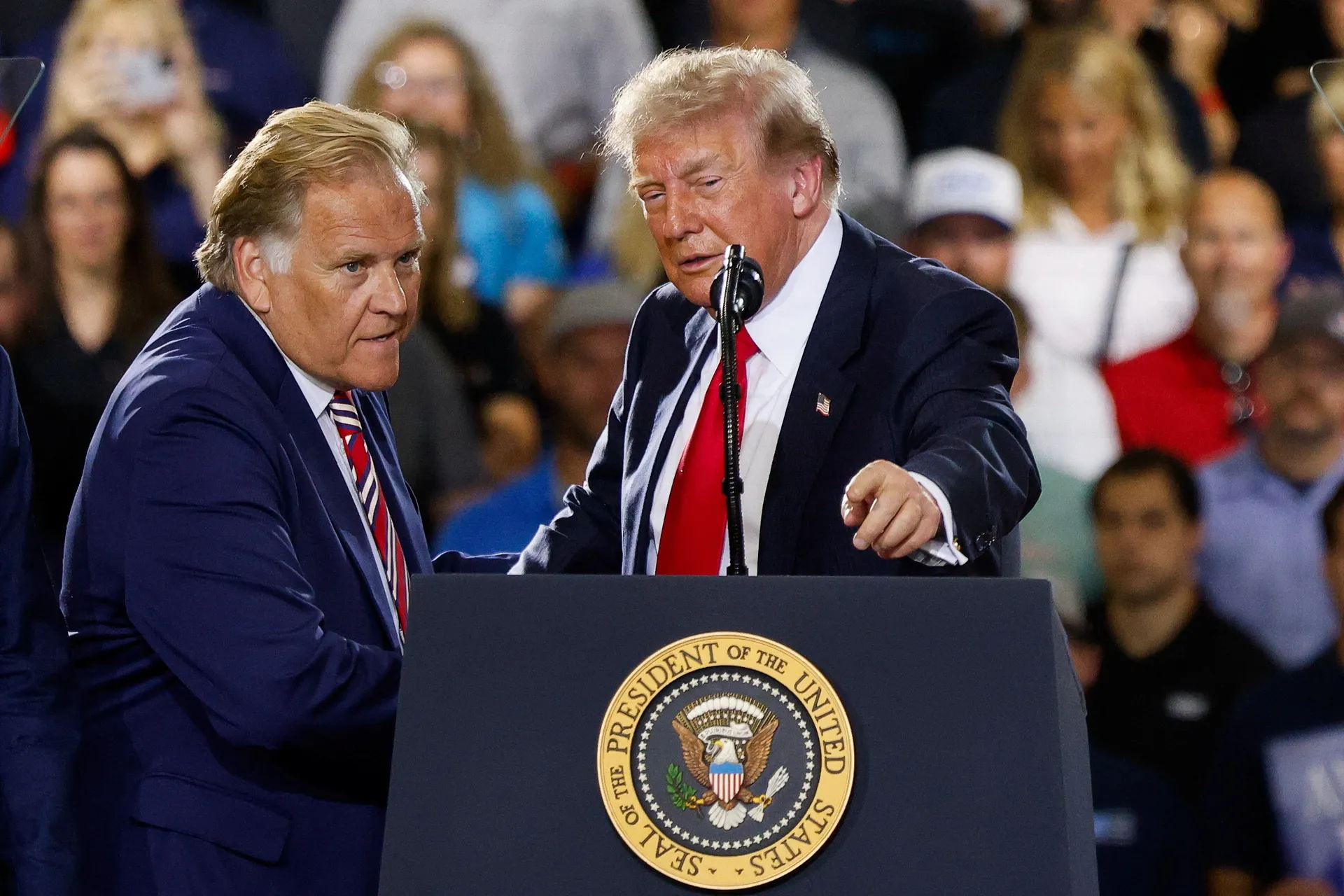 U.S. President Donald Trump stands with Former U.S. Representative Mike Rogers, as Trump delivers remarks on the economy, at the General Motors Proving Ground in Milford, Michigan, U.S. July 27, 2026.  REUTERS/Carlos Osorio