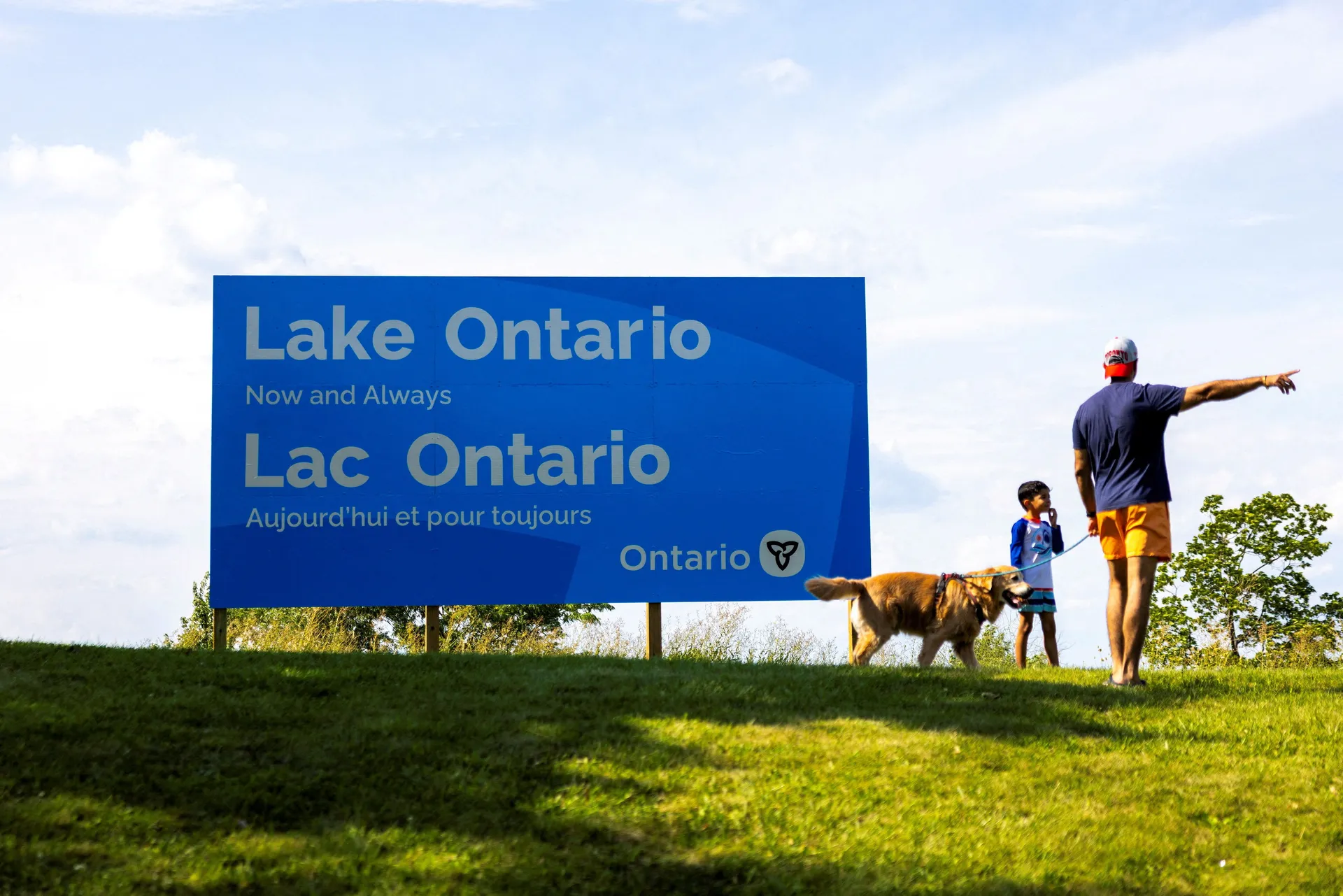 A family walks by a sign reading "Lake Ontario, Now and Always," unveiled by Ontario Premier Doug Ford at Fifty Point Conservation Area, after U.S. President Donald Trump signed an executive order renaming Lake Ontario as "Lake America," near Grimsby, Ont