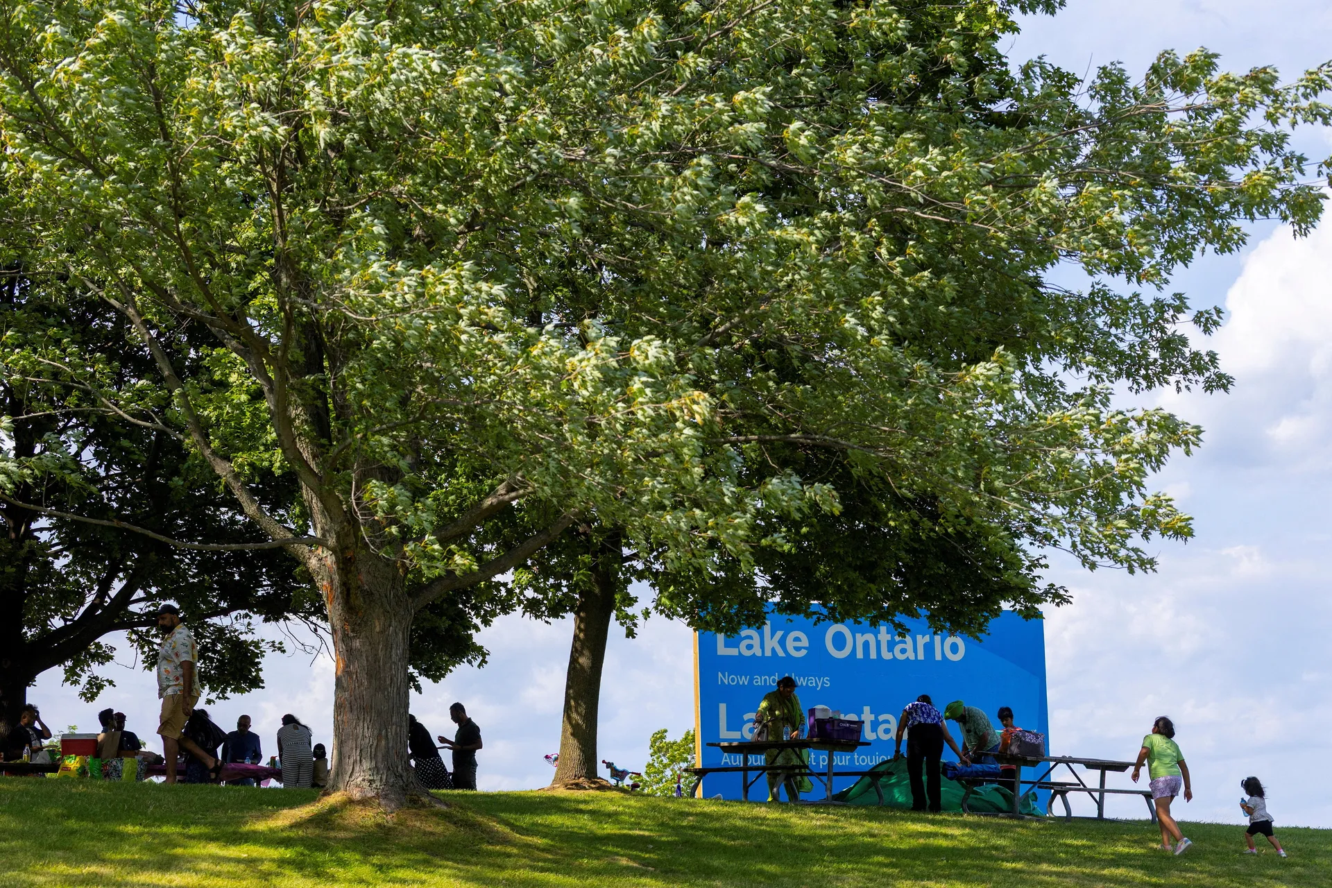 People sit near a sign reading "Lake Ontario, Now and Always," unveiled by Ontario Premier Doug Ford at Fifty Point Conservation Area, after U.S. President Donald Trump signed an executive order renaming Lake Ontario as "Lake America," near Grimsby, Ontar