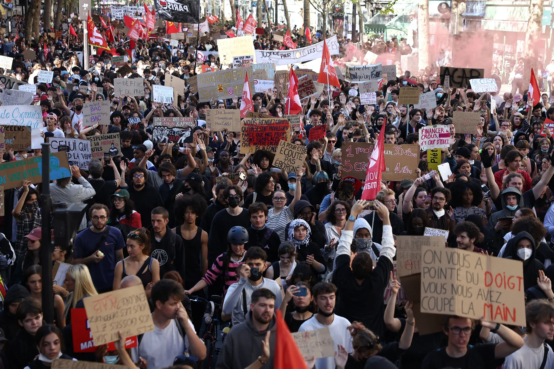 Protesters hold placards and flags during a demonstration by high school and university students, supported by teachers' union and school parents, in Paris as part of a nationwide day of protests and blockades, voicing anger over overcrowded classrooms, t