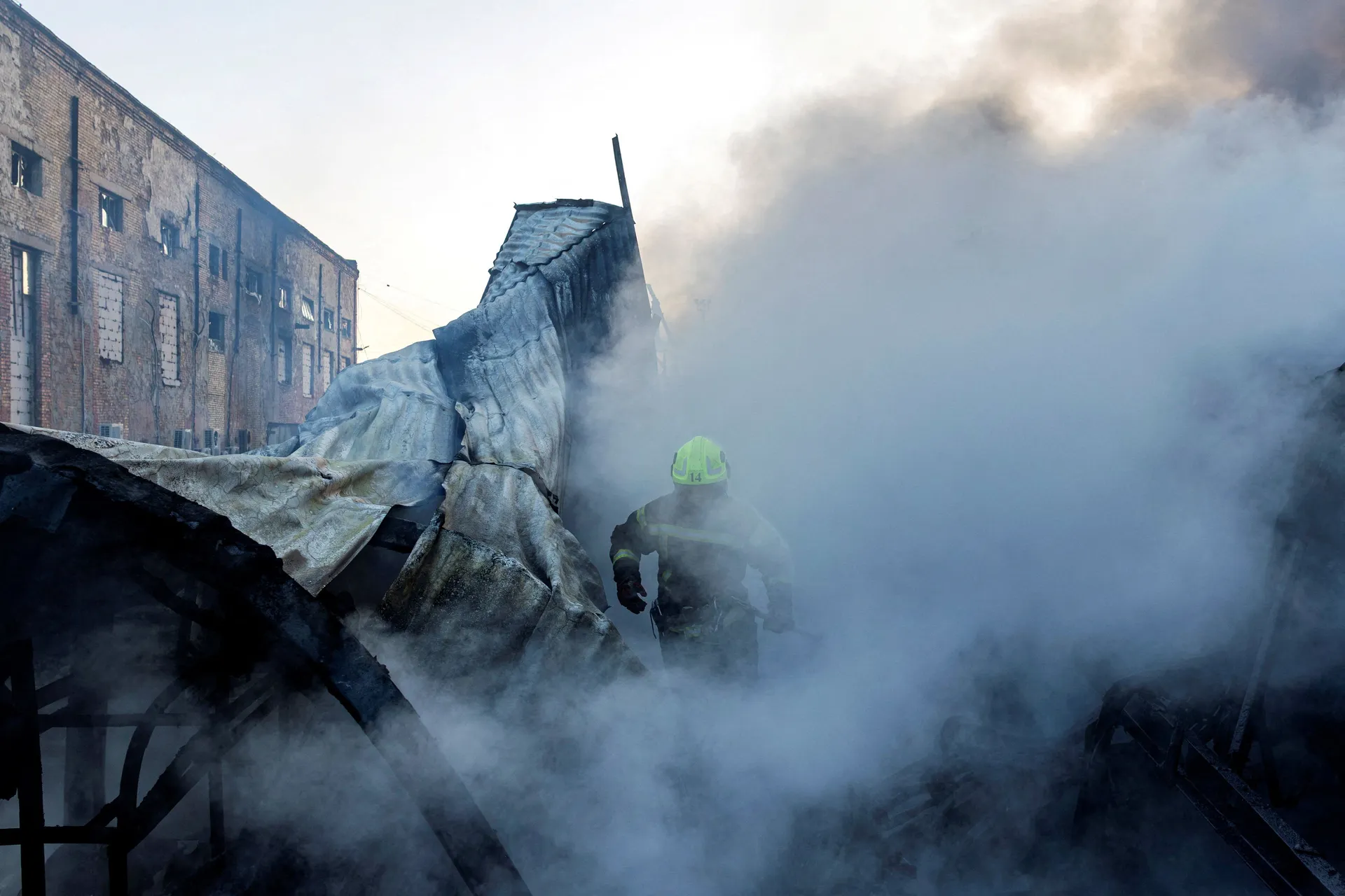 A firefighter walks through the smoke at the site of a warehouse that burned out after it was hit during a night of Russian missile attacks, amid Russia's attack on Ukraine, in Kyiv, Ukraine, October 7, 2026. REUTERS/Thomas Peter      TPX IMAGES OF THE DA