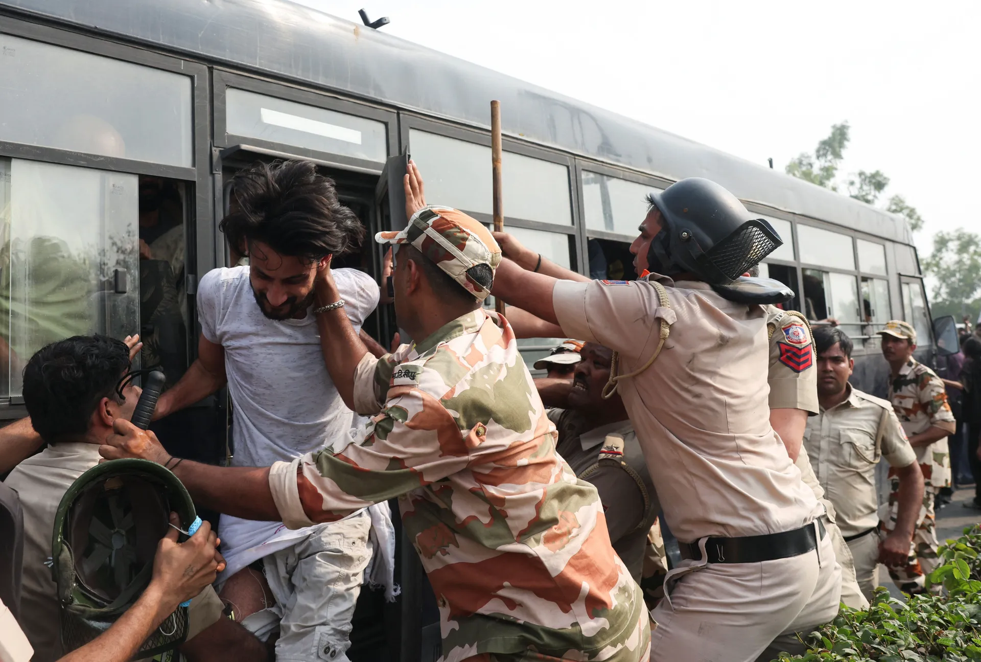 Security personnel try to stop a protester trying to get off the police bus after being detained, during a protest organised by the Cockroach Janta Party (CJP) seeking the resignation of India's Chief Election Commissioner, Gyanesh Kumar, in New Delhi, In