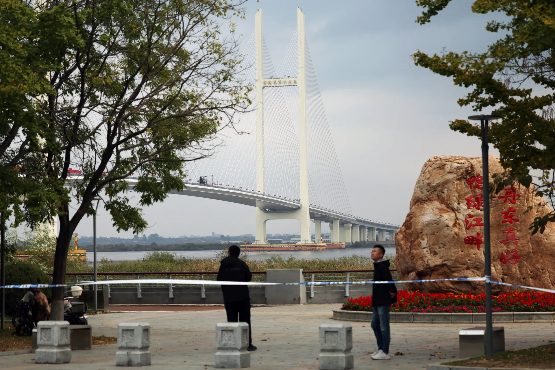 Security personnel keep watch at a cordoned-off waterfront before the opening ceremony for the New Yalu River Bridge, which connects China’s Dandong New Zone and North Korea’s Sinuiju, in Dandong, Liaoning province, China October 15, 2026. REUTERS/Florenc