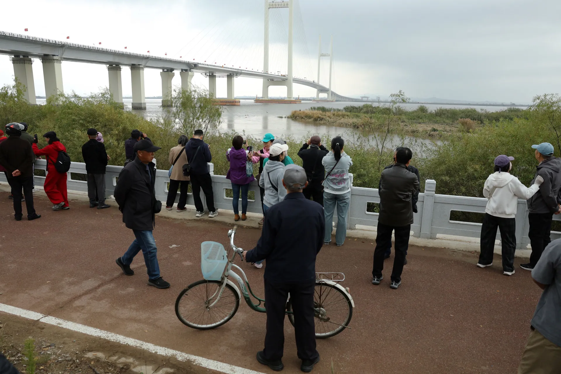 Residents look at the newly opened New Yalu River Bridge, which connects China's Dandong New Zone and North Korea's Sinuiju, in Dandong, Liaoning province, China October 15, 2026. REUTERS/Florence Lo