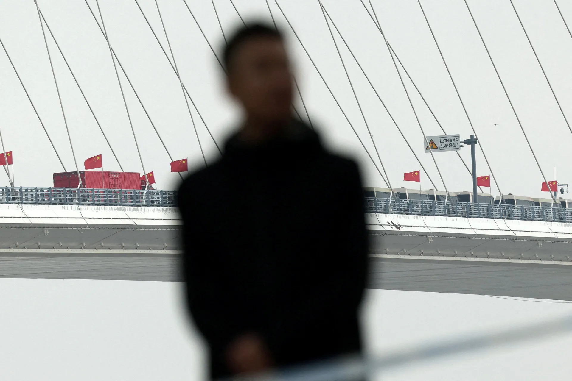 A security member keeps watch at a cordoned-off waterfront during the opening ceremony for the New Yalu River Bridge, which connects China’s Dandong New Zone and North Korea’s Sinuiju, in Dandong, Liaoning province, China October 15, 2026. REUTERS/Florenc