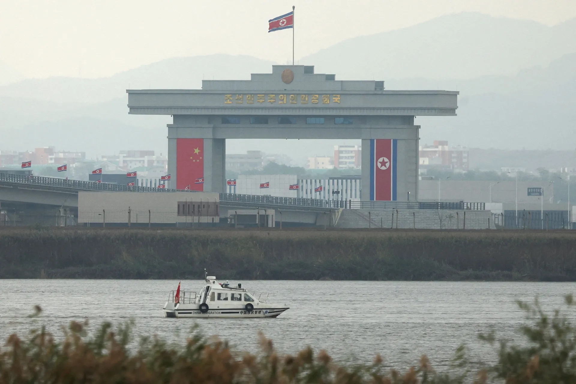 A China Immigration inspection vessel travels along the Yalu river past a North Korean customs building at the end of the newly opened New Yalu River Bridge, which connects North Korea's Sinuiju from China's Dandong New Zone, as seen from Dandong, Liaonin